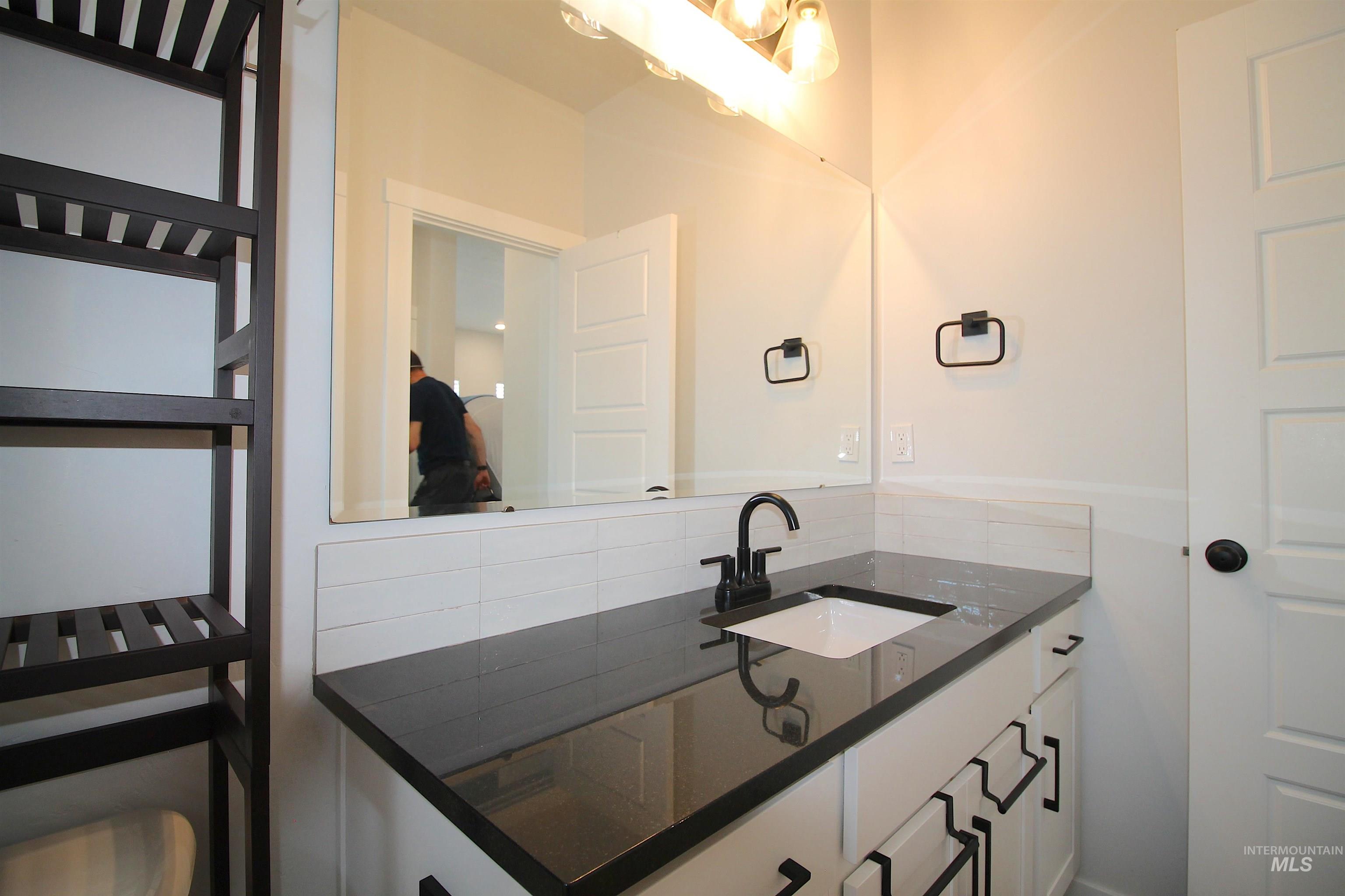 Bathroom vanity featuring a dark countertop, undermount sink, and matte black faucet