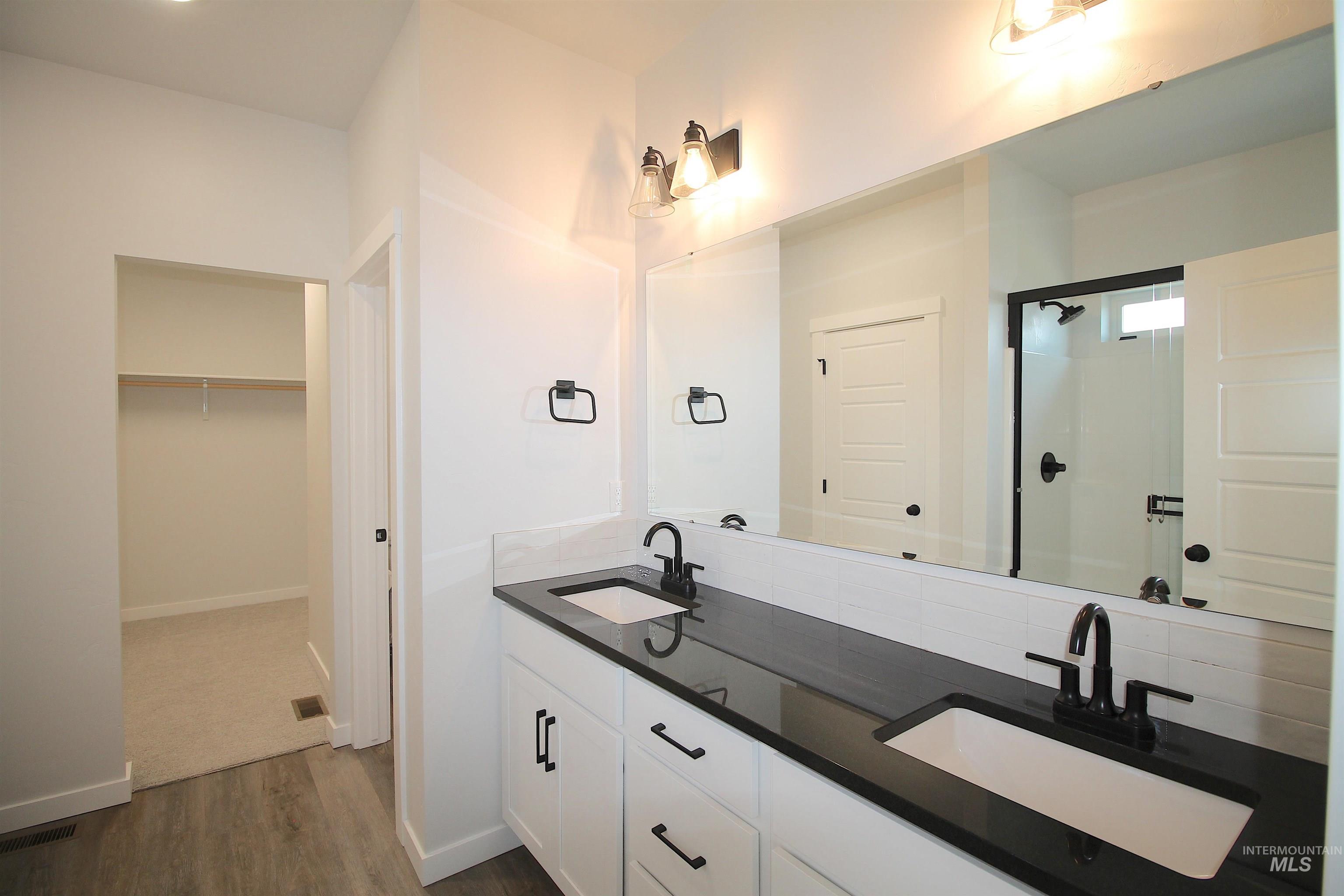 Double vanity featuring white cabinetry, black countertops, undermount sinks, and matte black fixtures