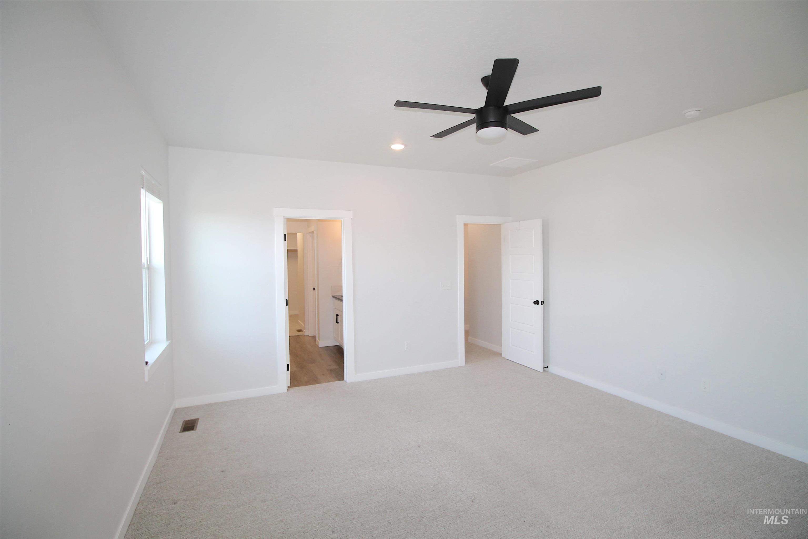 Spacious room featuring light-toned carpeting, a modern ceiling fan with integrated lighting, and recessed ceiling lighting