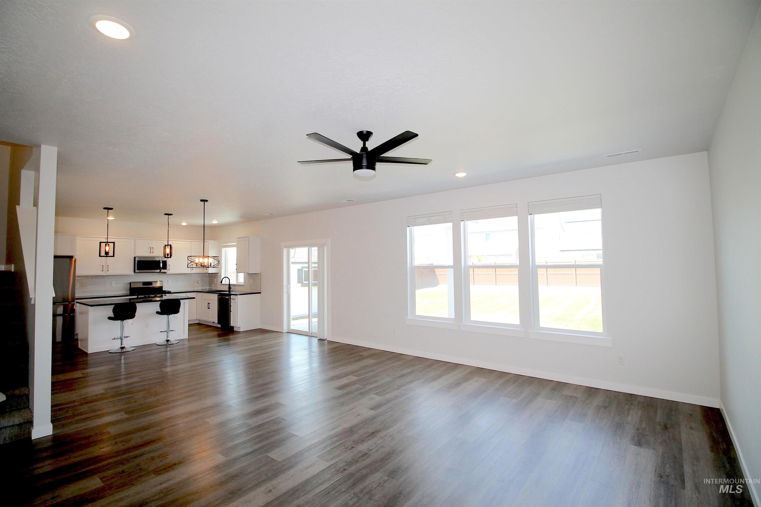 Spacious open-concept living area featuring wood-finish flooring, recessed lighting, and a contemporary ceiling fan