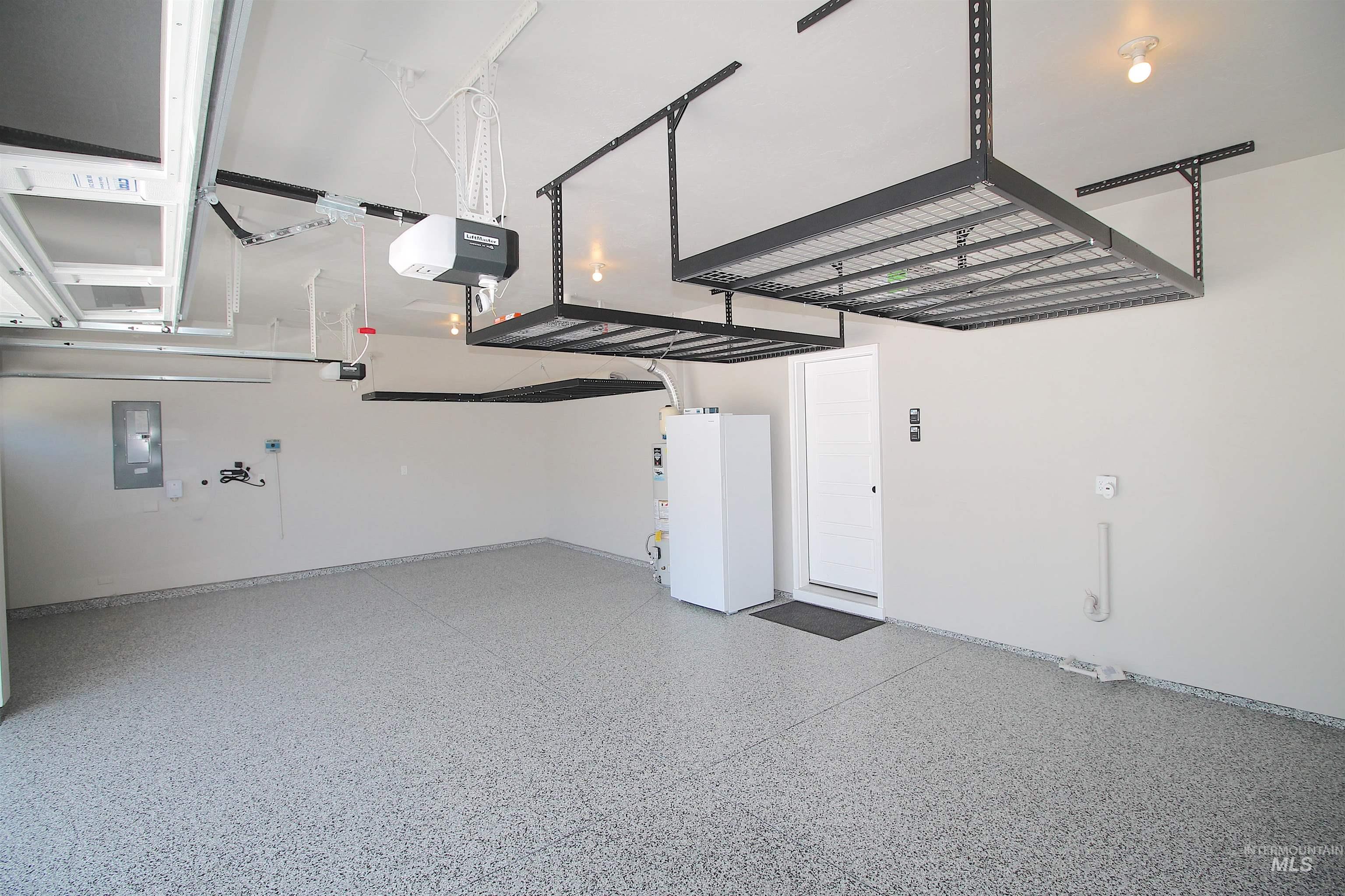 Spacious garage featuring a durable epoxy floor finish and overhead storage racks