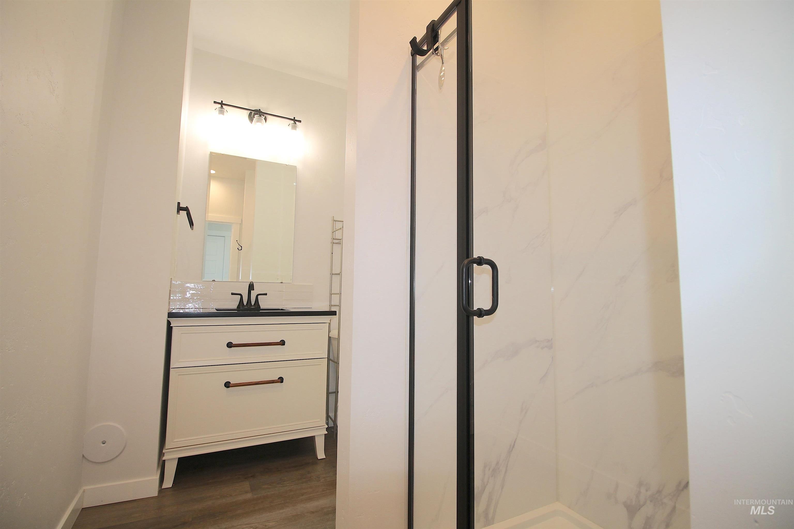 Bathroom featuring a freestanding vanity with a dark countertop and matte black hardware, a subway tile backsplash, and a framed mirror