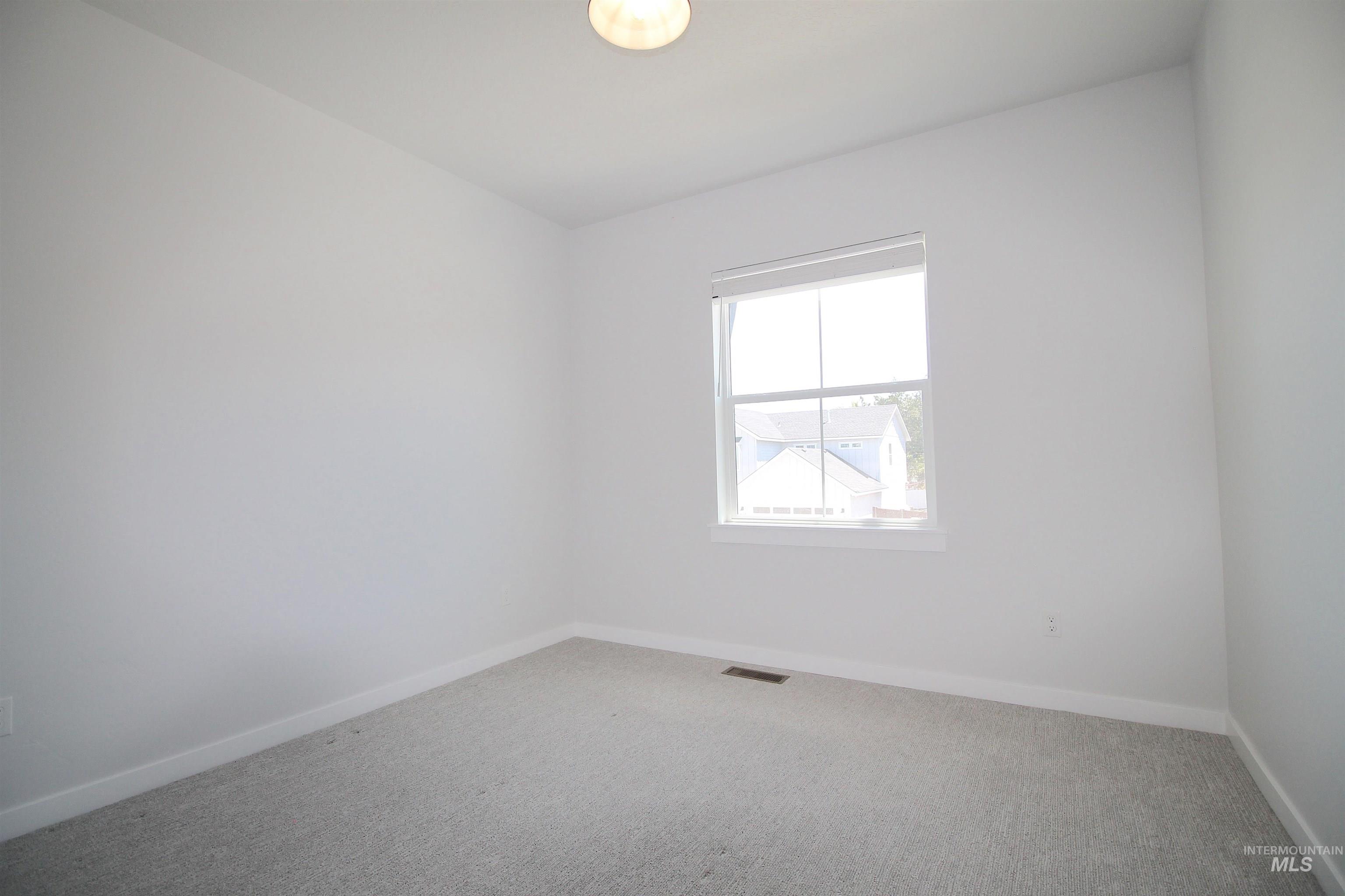 Bright interior space featuring a window with white trim, light gray carpeting, and neutral wall tones