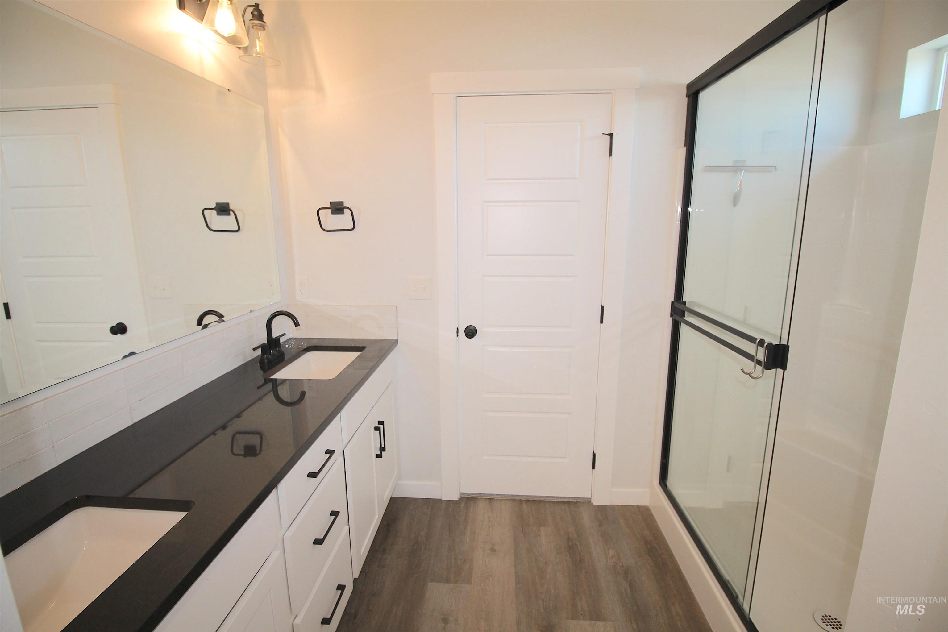 Dual vanity with integrated sinks and dark countertops, complemented by white cabinetry and matte black hardware