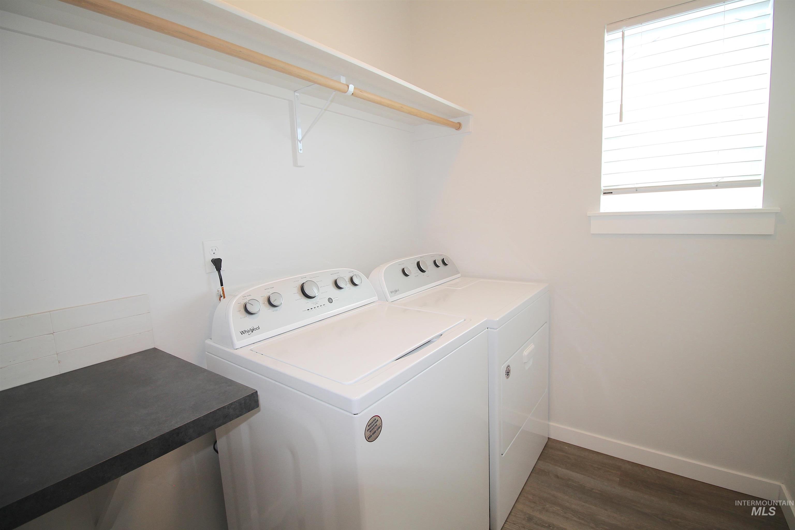 Dedicated laundry area featuring a white shelf, clothing rod, dark countertop, and wood-finish flooring