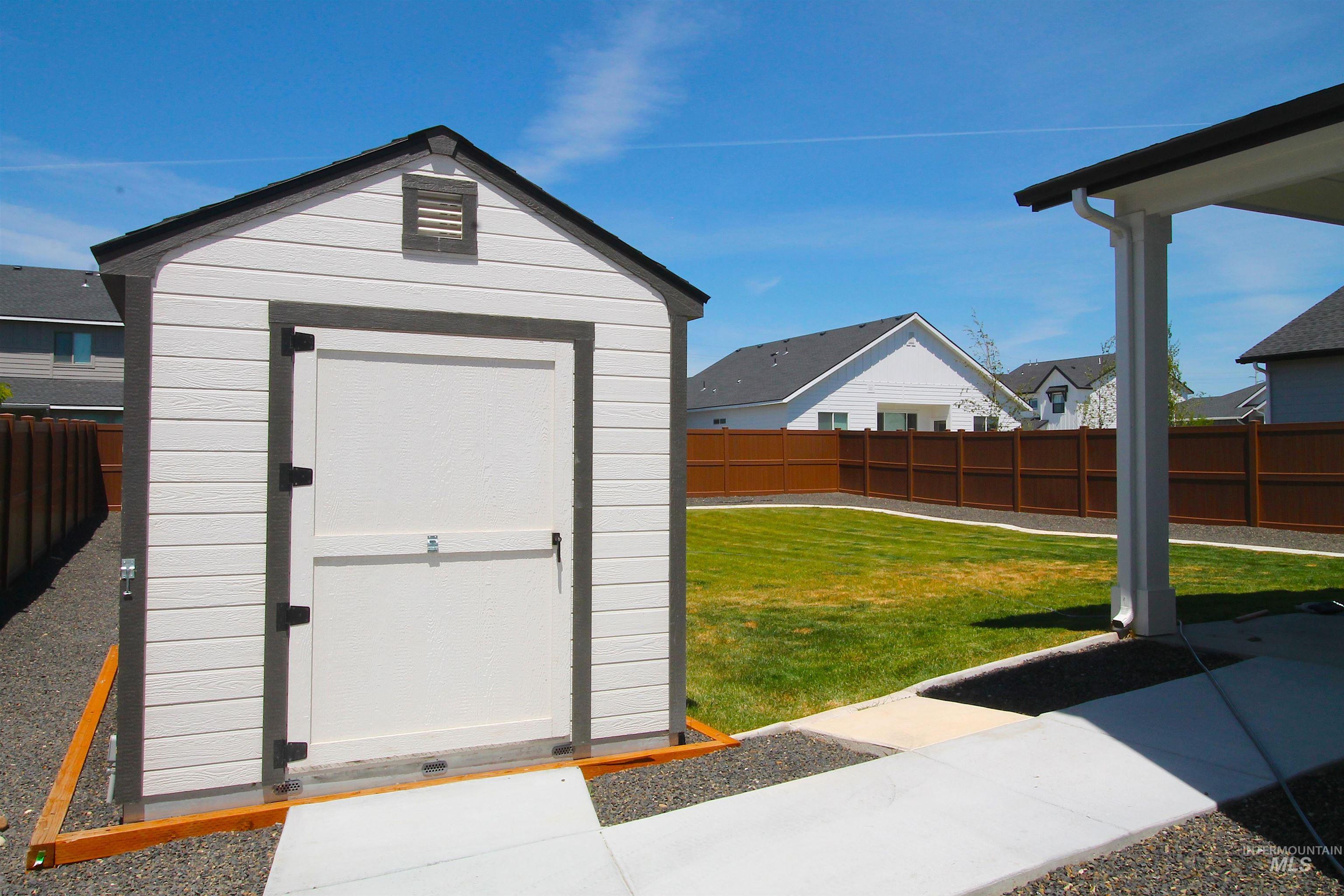 White storage shed with dark trim, featuring a gable roof and louvered vent