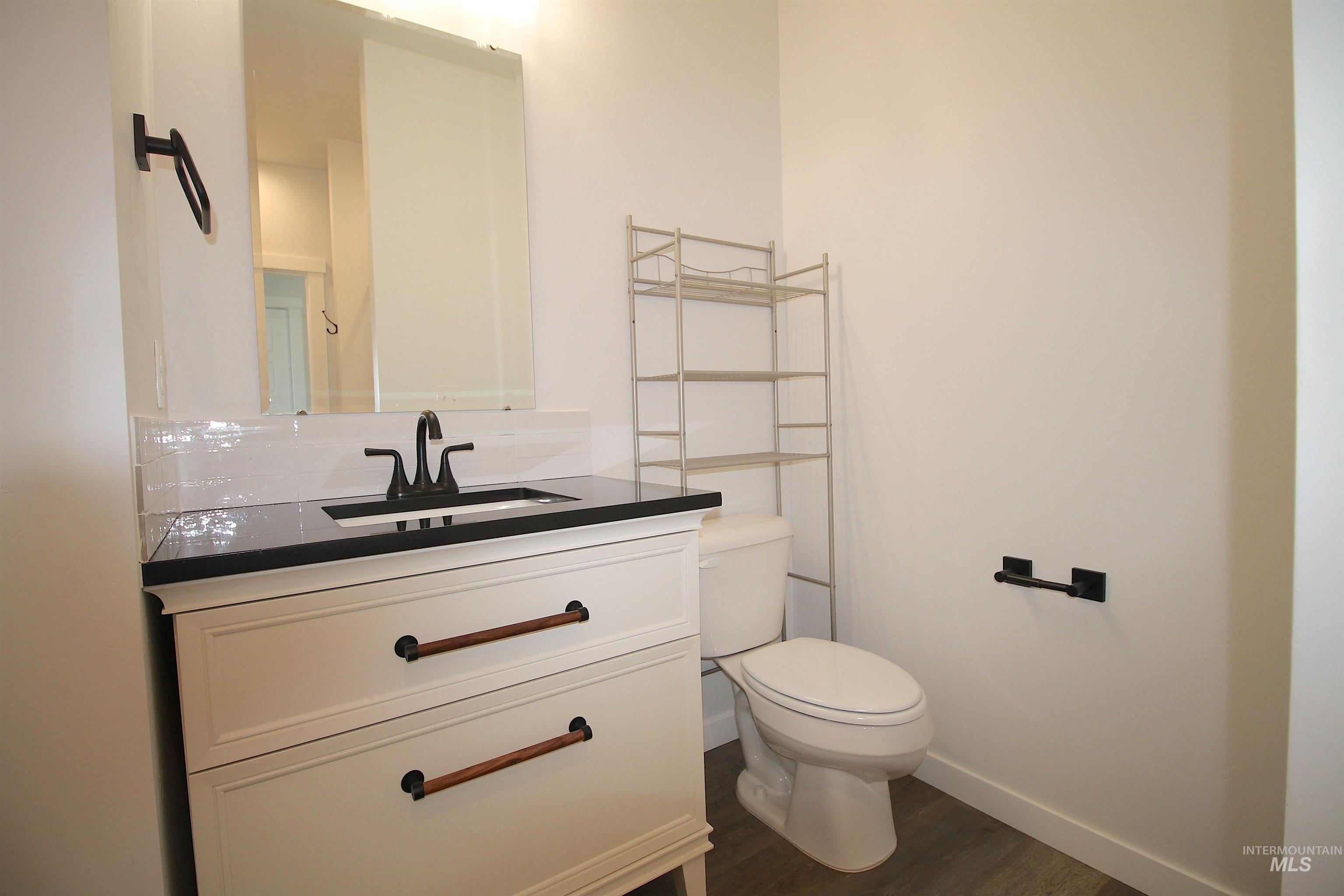 Vanity with dark countertop, integrated sink, and matte black faucet