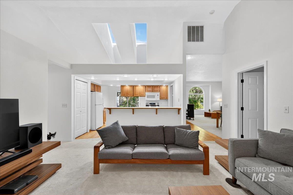 Living area featuring light carpet, a towering ceiling, and a skylight