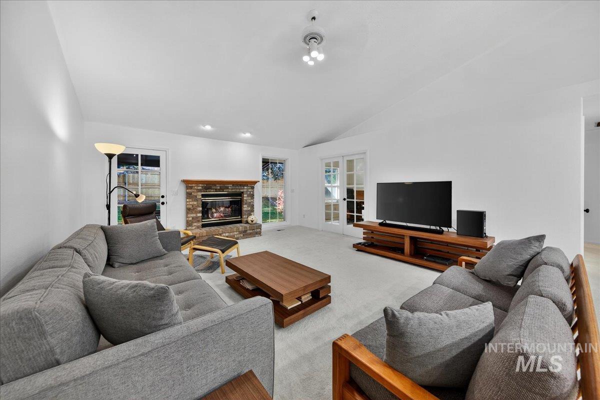 Carpeted living room featuring vaulted ceiling and a fireplace