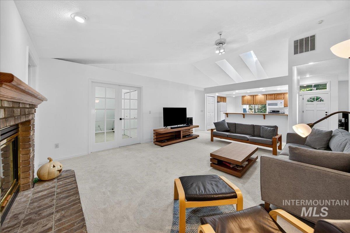 Living room with carpet flooring, vaulted ceiling, and a fireplace