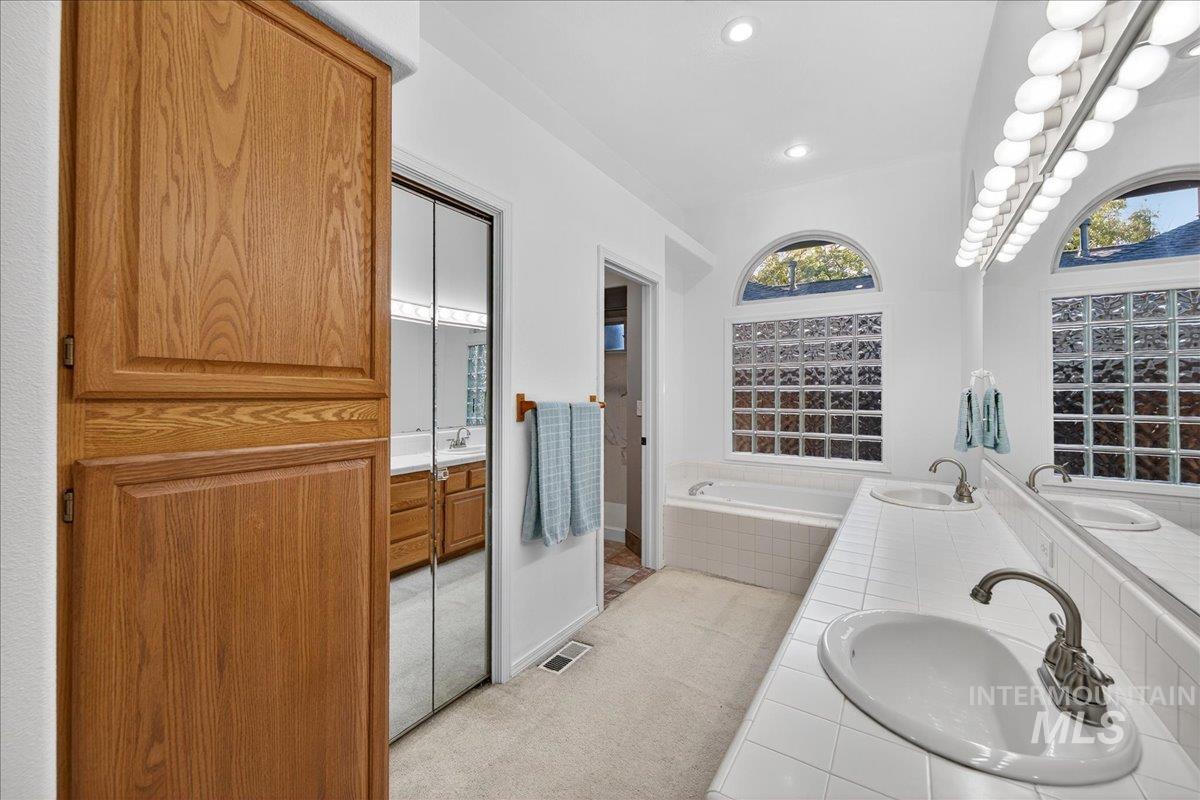 Full bathroom featuring double vanity, a bath, and recessed lighting