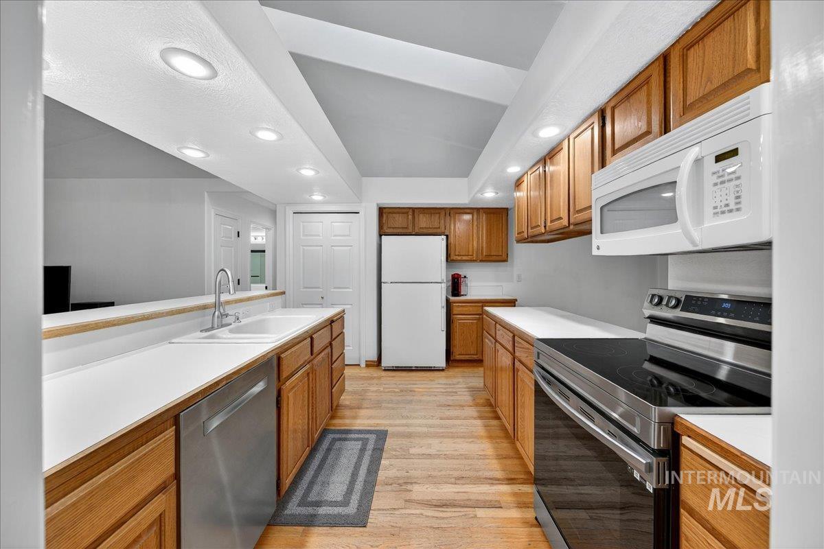 Kitchen featuring appliances with stainless steel finishes, recessed lighting, brown cabinets, light wood-style flooring, and light countertops