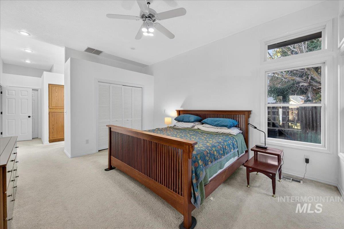 Bedroom with light colored carpet, ceiling fan, and a closet