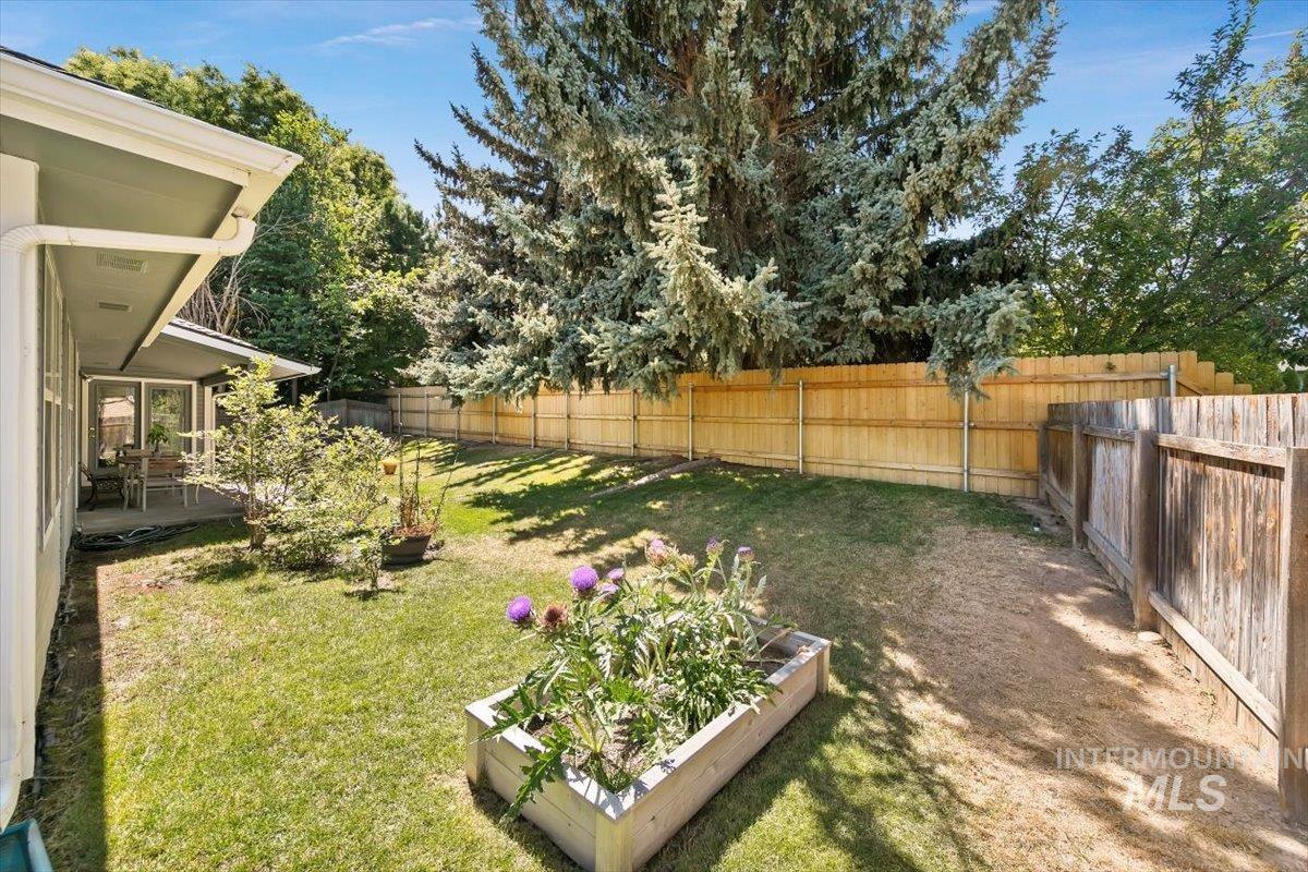 Fenced backyard featuring a patio and a vegetable garden