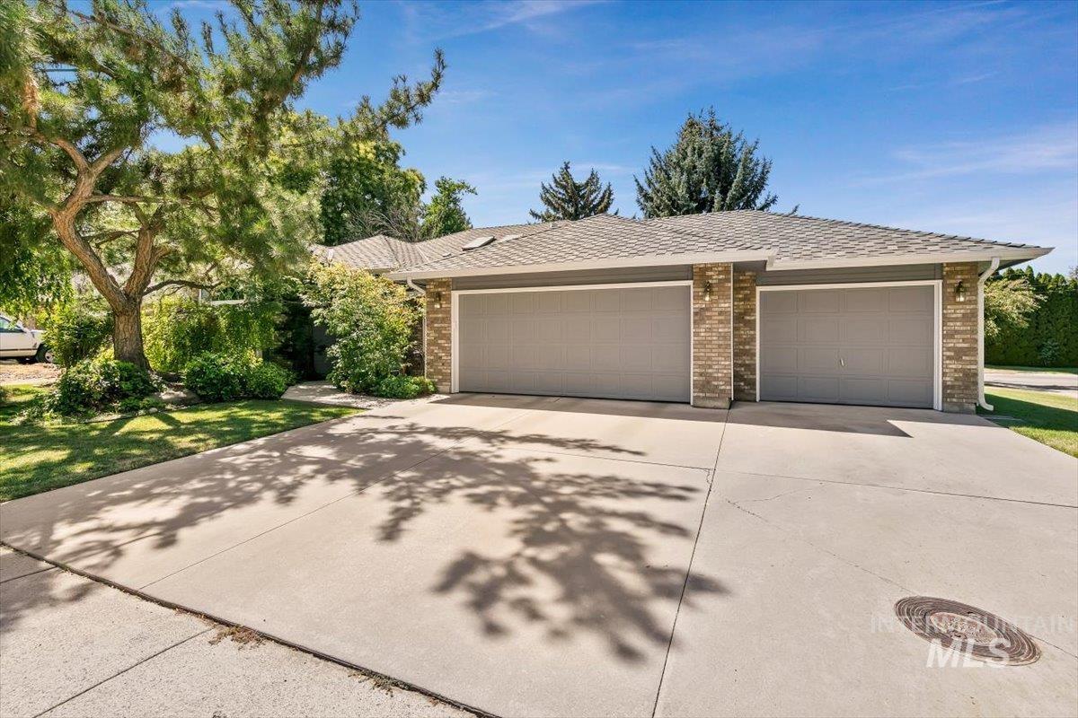 View of front of house with an attached garage, driveway, and brick siding