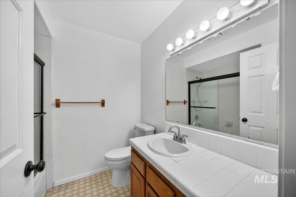 Bathroom featuring vanity, a shower with shower door, and light flooring