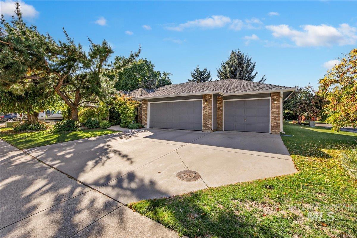 View of front of house featuring driveway, an attached garage, a front yard, and brick siding
