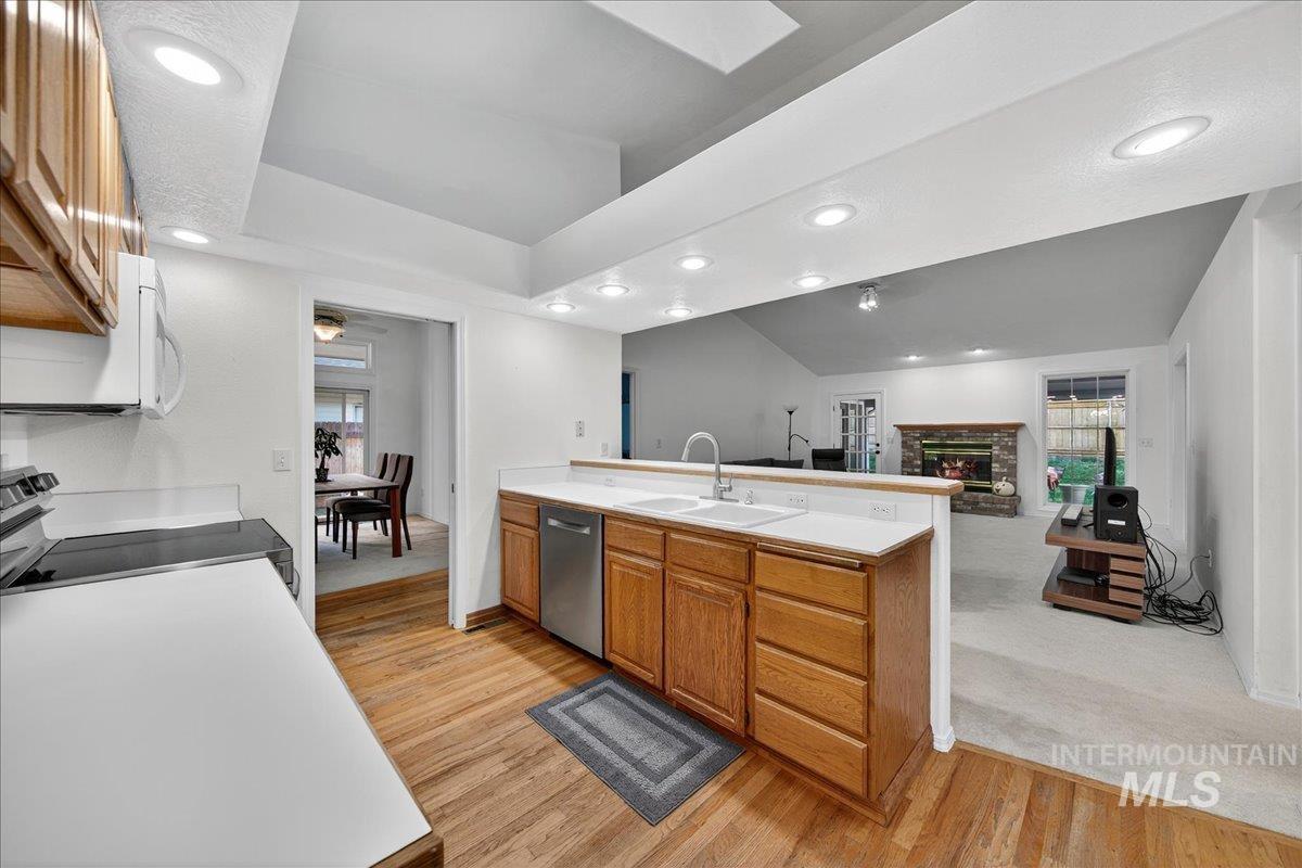 Kitchen with brown cabinets, light countertops, a peninsula, light wood-style flooring, and recessed lighting