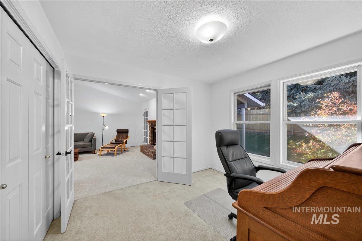 Office space featuring light colored carpet, a textured ceiling, french doors, and lofted ceiling
