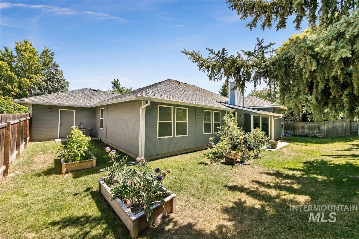 Rear view of property featuring a fenced backyard, a vegetable garden, roof with shingles, a chimney, and a patio