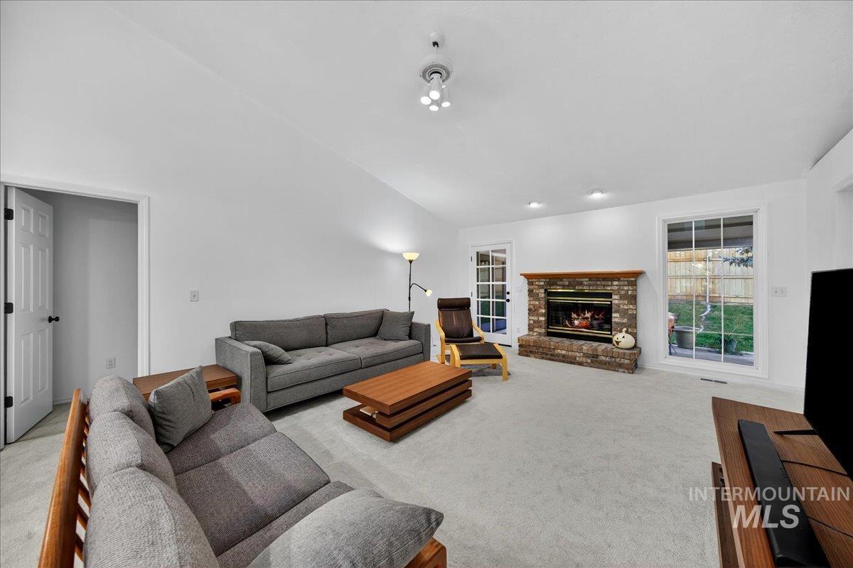 Living room featuring light carpet, a fireplace, and vaulted ceiling