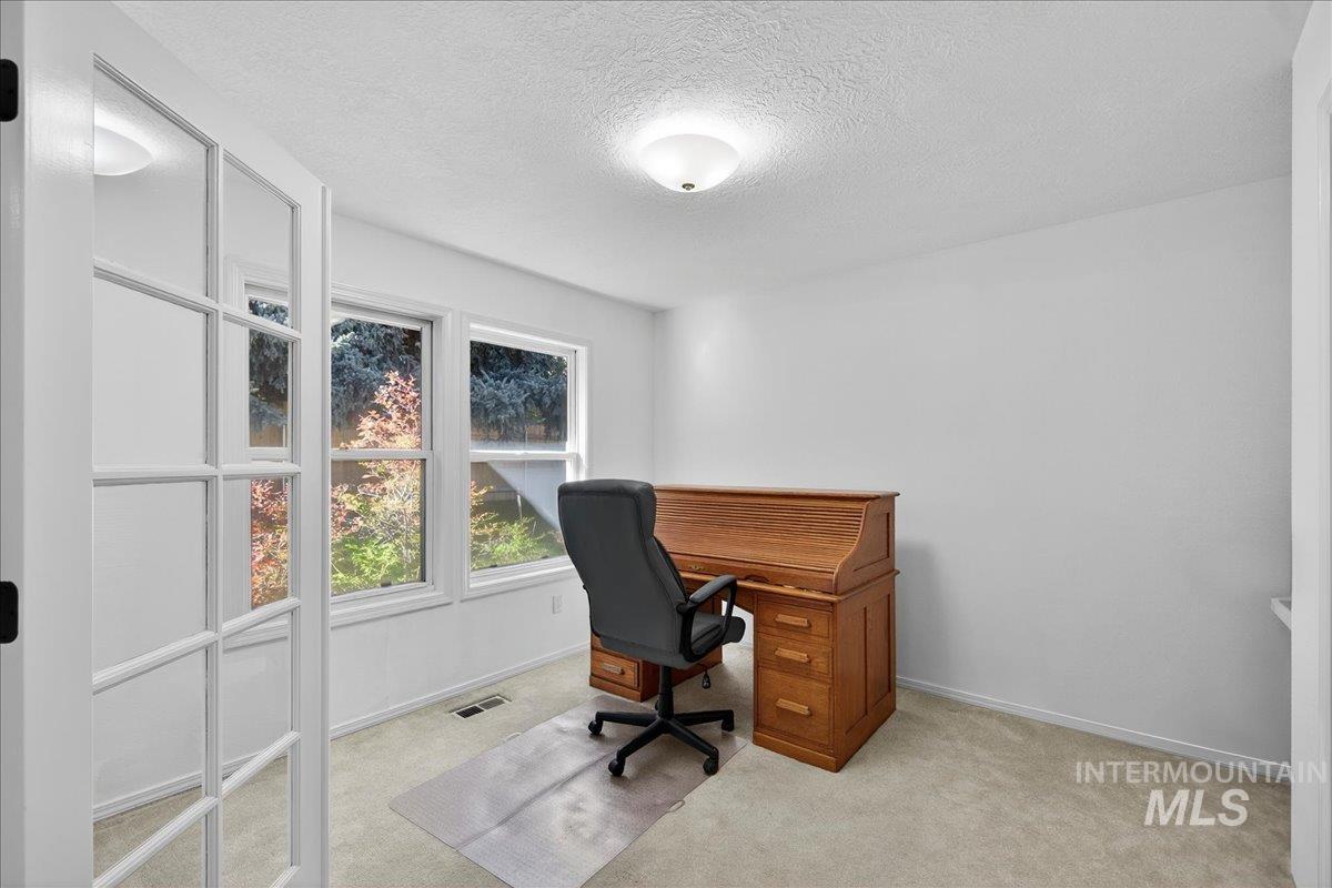 Home office featuring a textured ceiling and light carpet