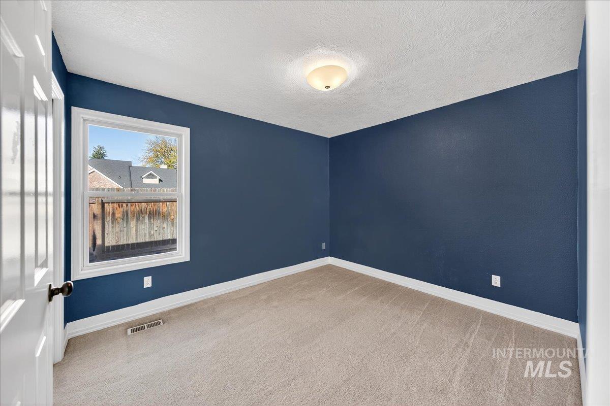 Unfurnished room with light carpet and a textured ceiling