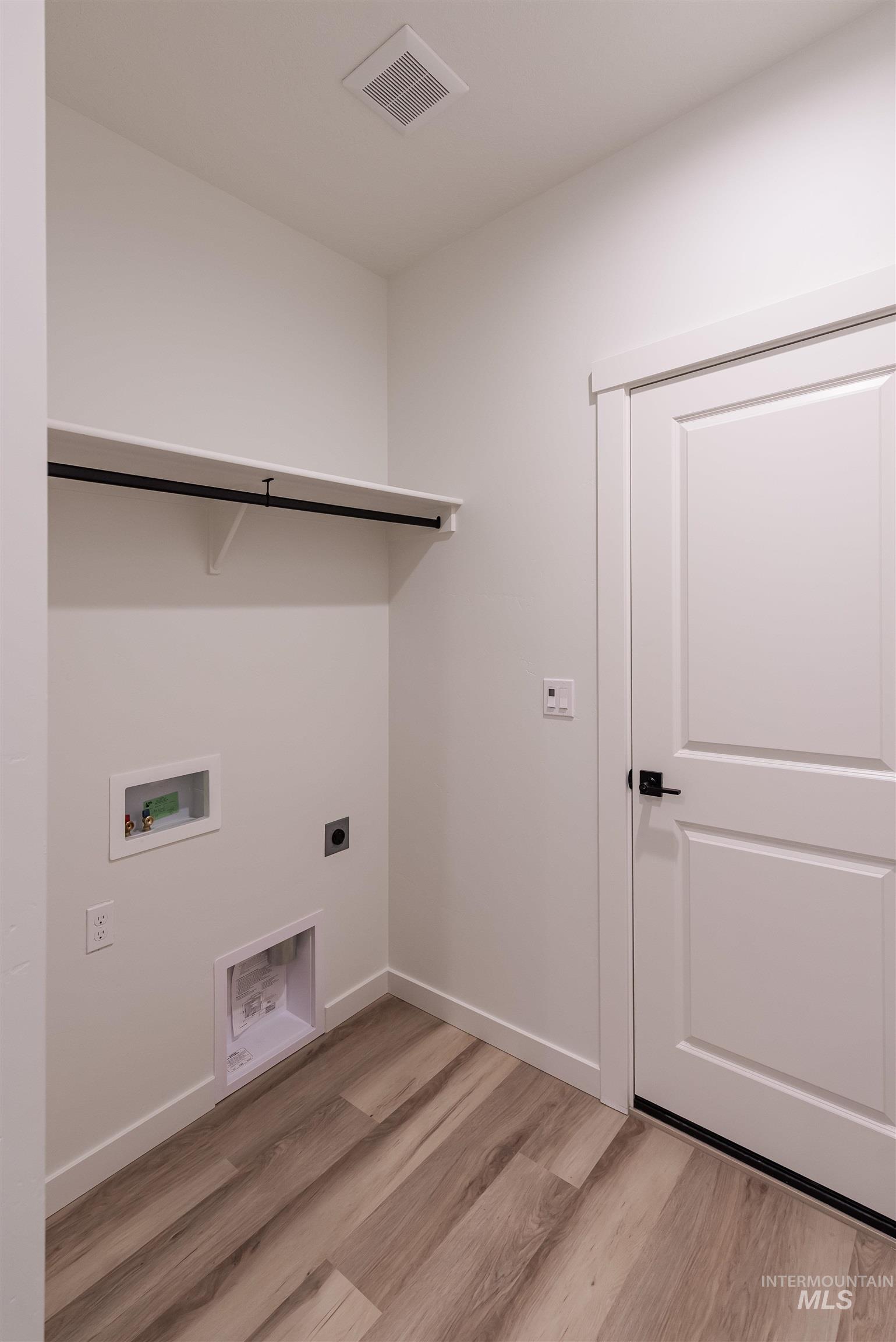 Laundry area with hookup for an electric dryer, light wood-style floors, and hookup for a washing machine
