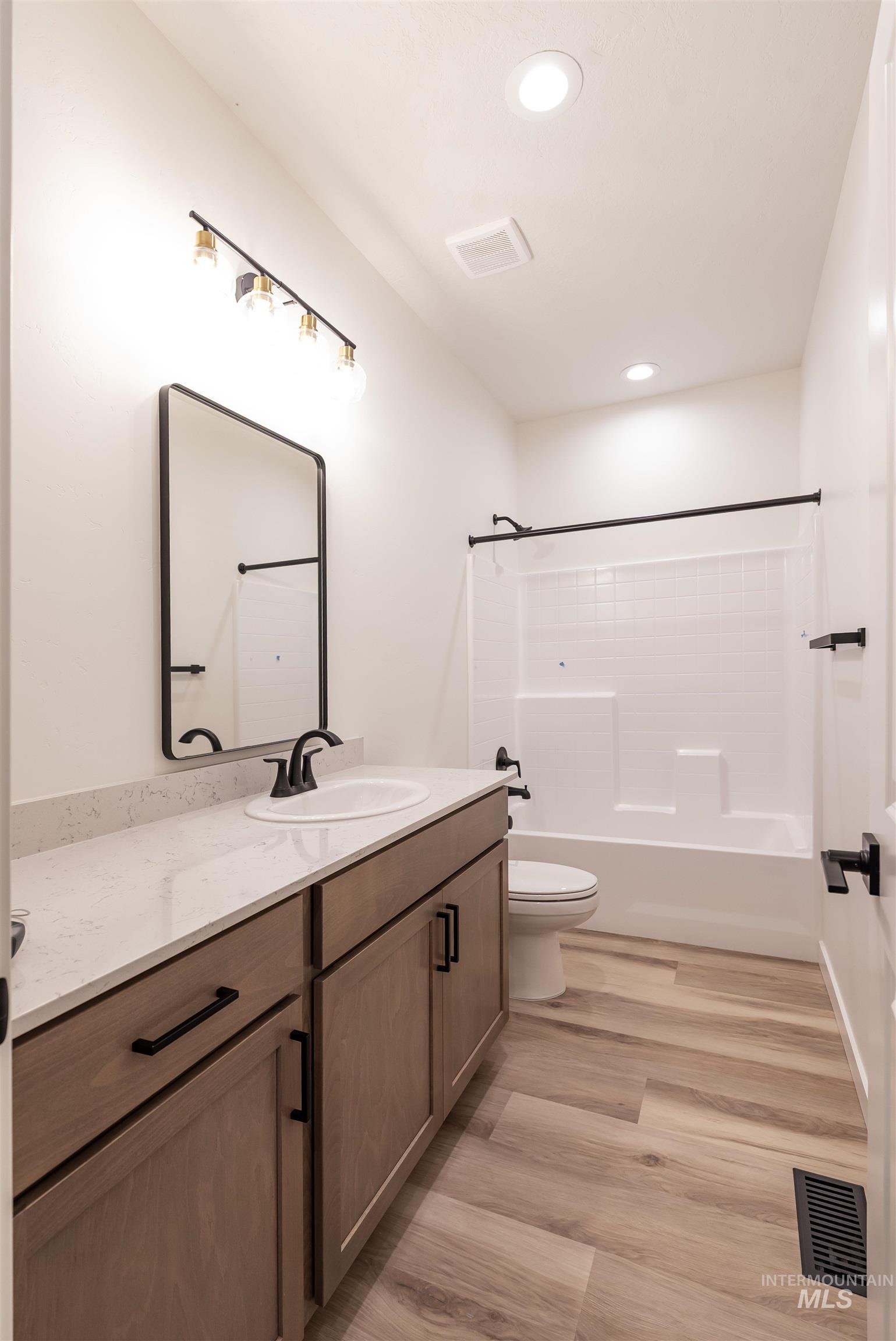 Bathroom with vanity, shower / bathtub combination, light wood-type flooring, and recessed lighting