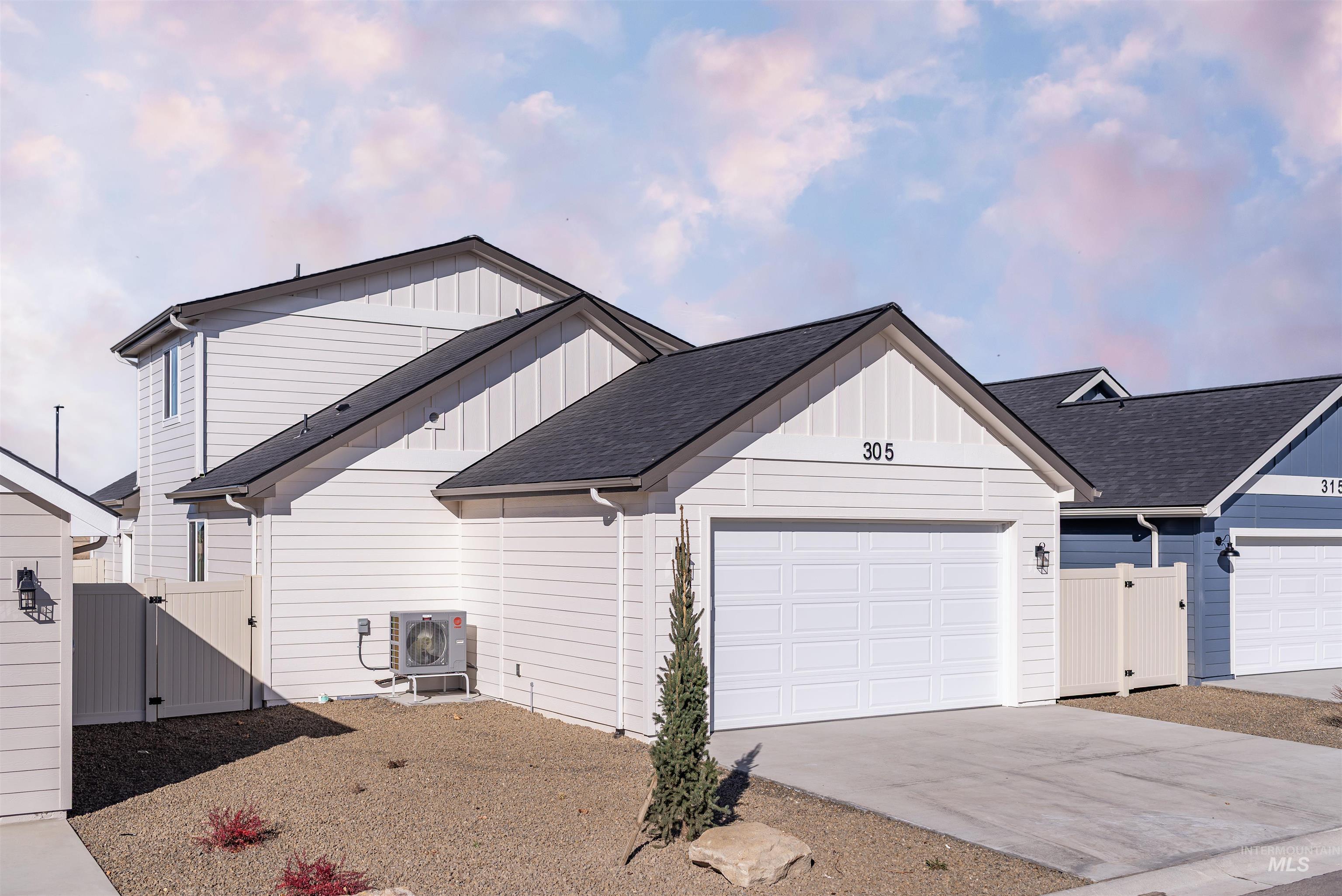 View of front of property featuring board and batten siding, a gate, roof with shingles, and concrete driveway