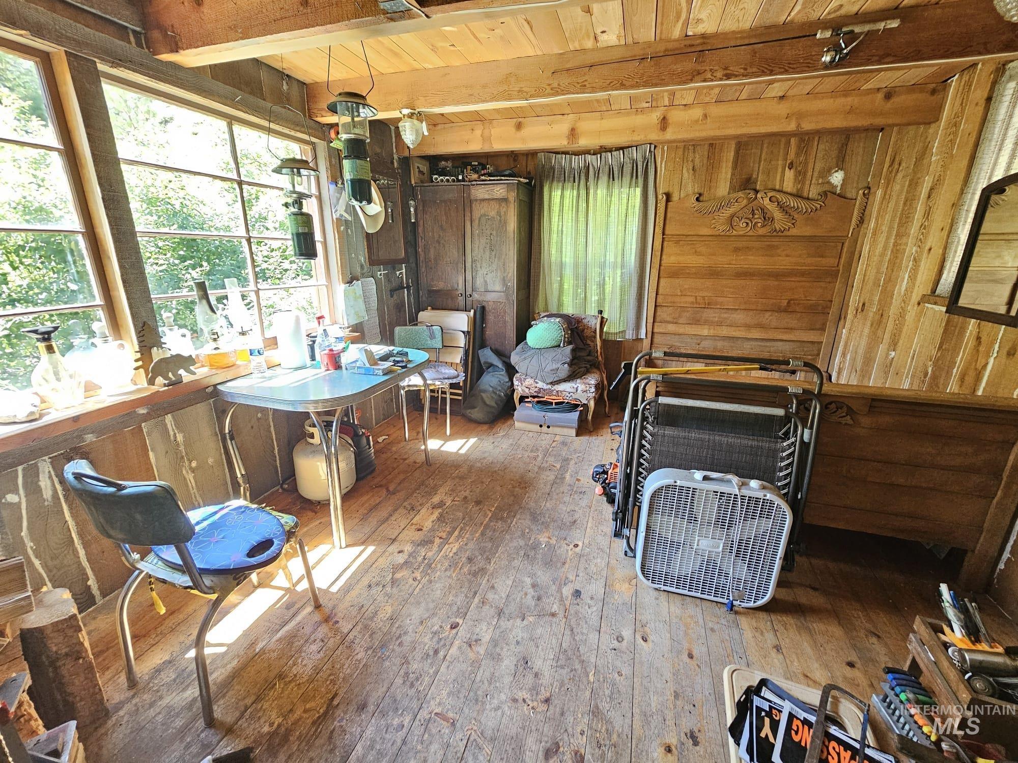 Dining room featuring wood walls, a wood ceiling with exposed beams, and hardwood / wood-style floors