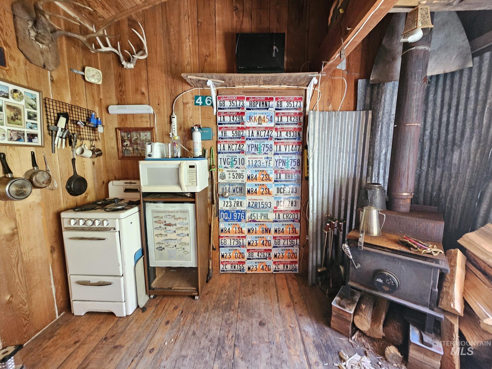 Kitchen with wood walls, white appliances, and hardwood / wood-style floors