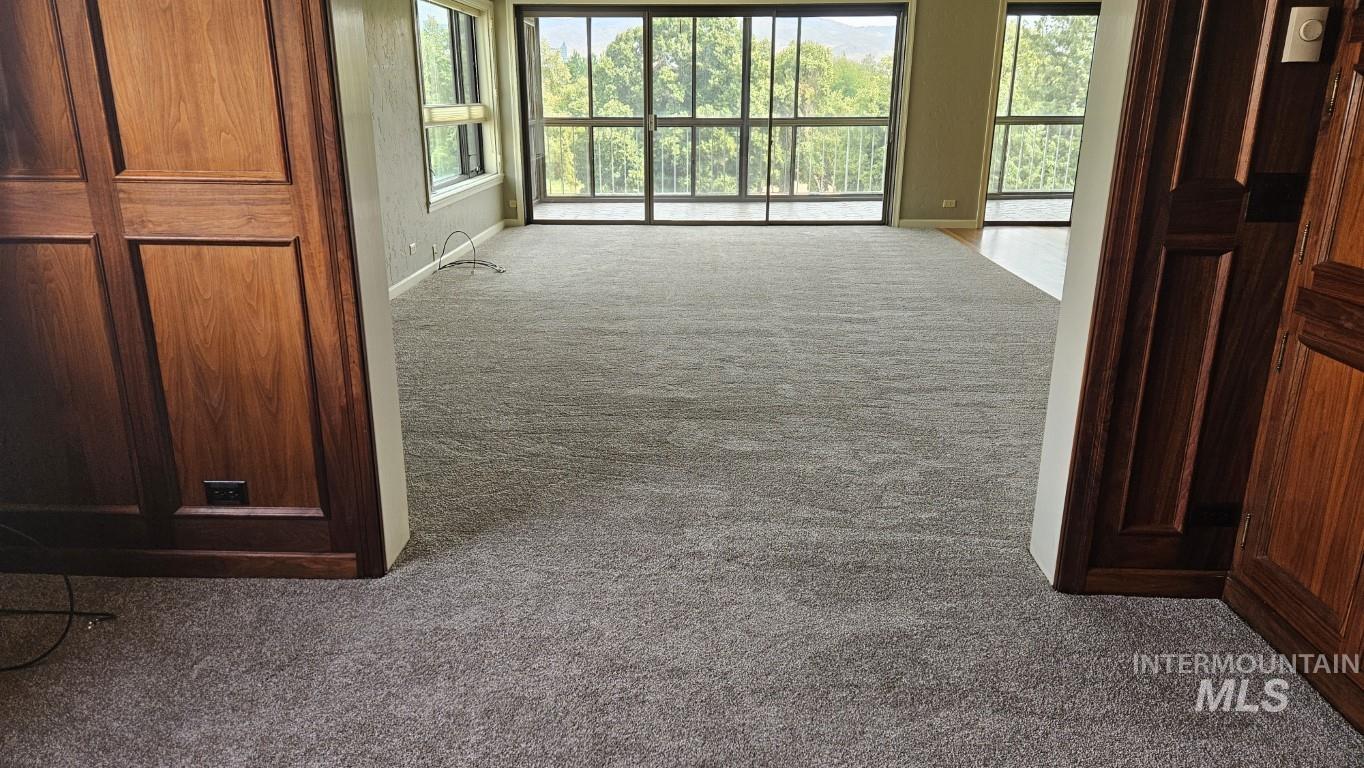 Hall featuring dark colored carpet and plenty of natural light