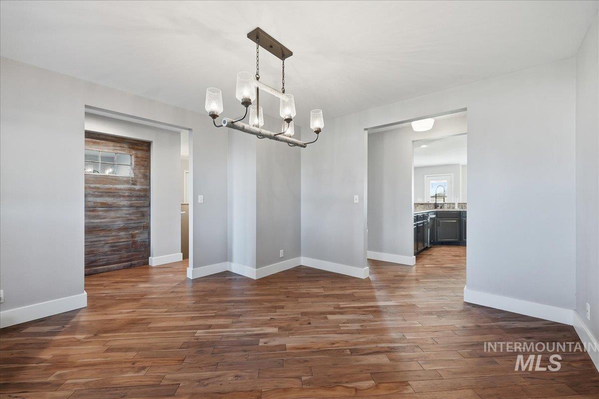 Unfurnished dining area with dark wood-style floors and a chandelier