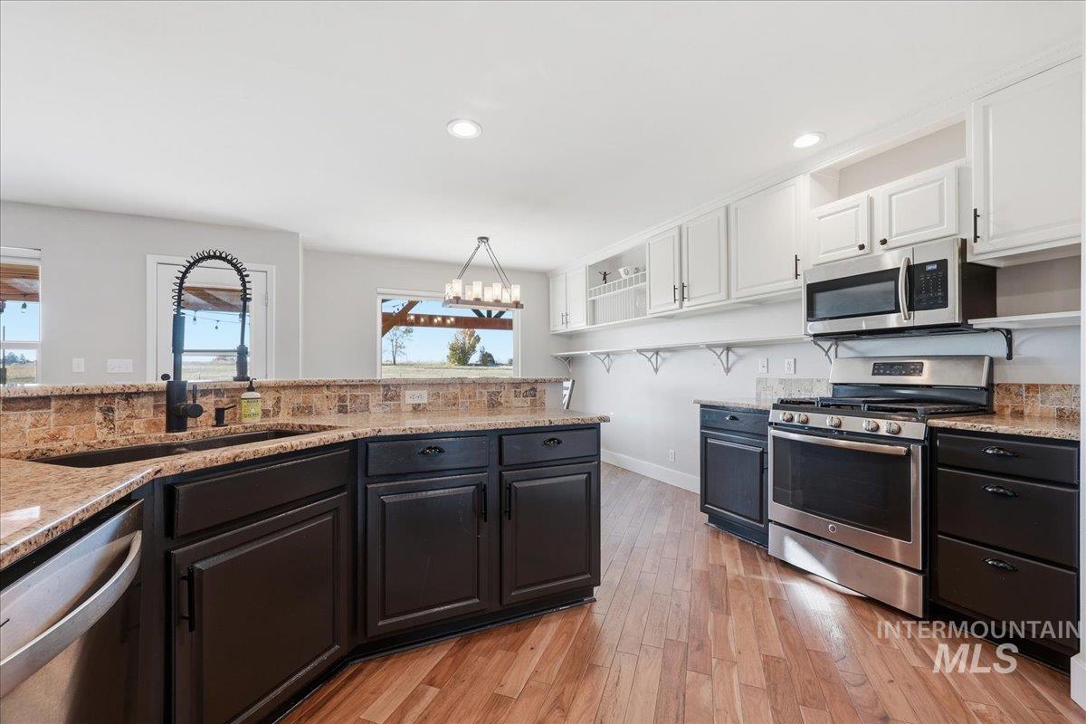 Kitchen featuring appliances with stainless steel finishes, light wood-style flooring, white cabinetry, recessed lighting, and light stone countertops