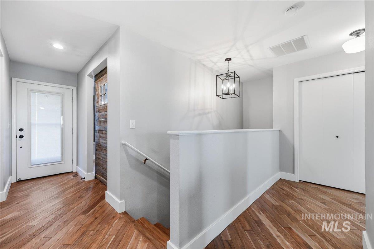 Corridor featuring an upstairs landing, wood finished floors, a chandelier, and recessed lighting