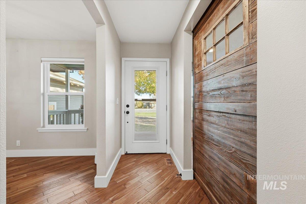 Doorway with wood finished floors and baseboards