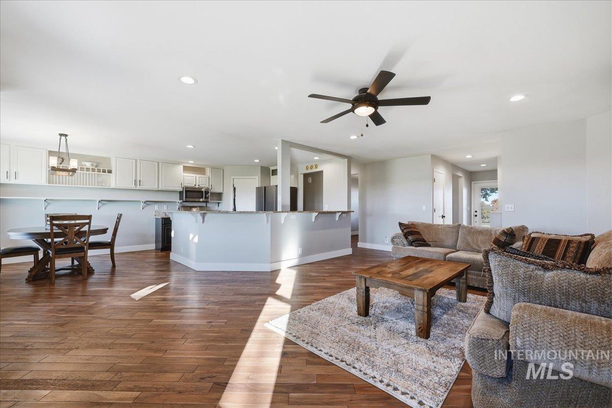 Living area featuring ceiling fan, recessed lighting, and dark wood-style flooring