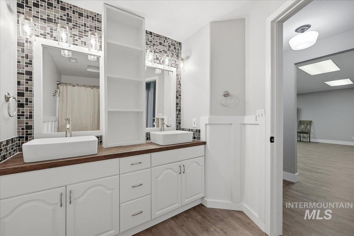 Full bath with double vanity, wood finished floors, and a shower with curtain