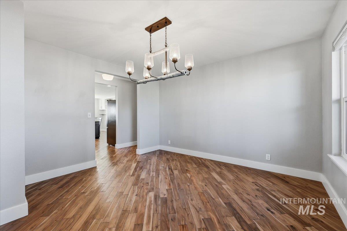 Empty room featuring dark wood-style floors and a chandelier