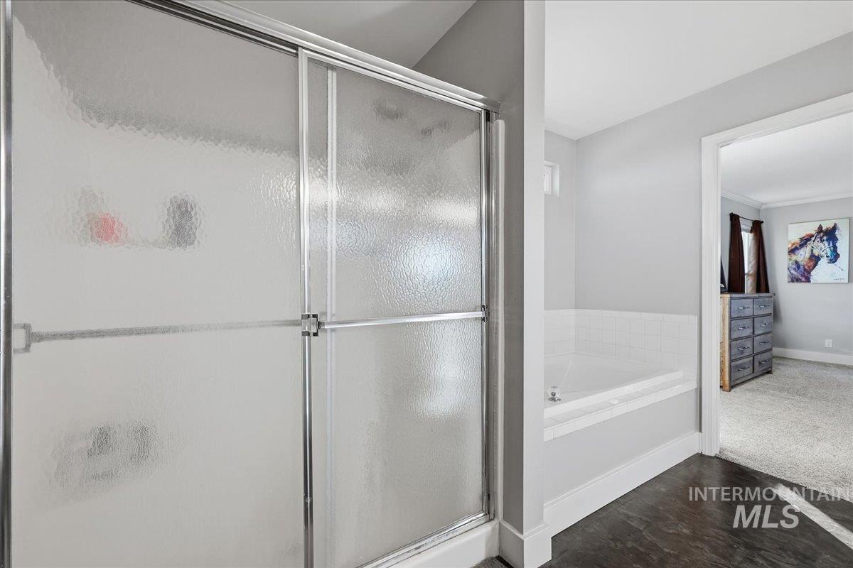 Full bathroom featuring a shower stall, a bath, and dark wood-style floors