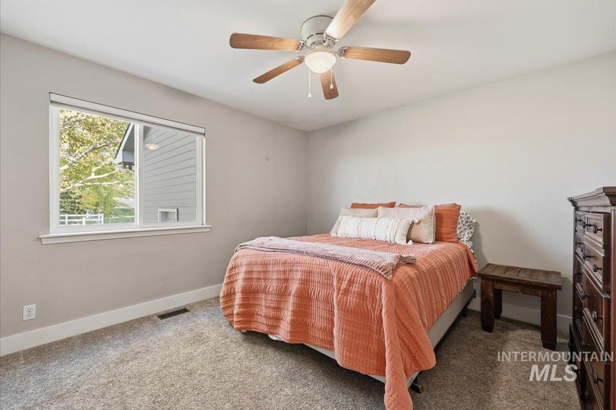 Carpeted bedroom with baseboards and a ceiling fan