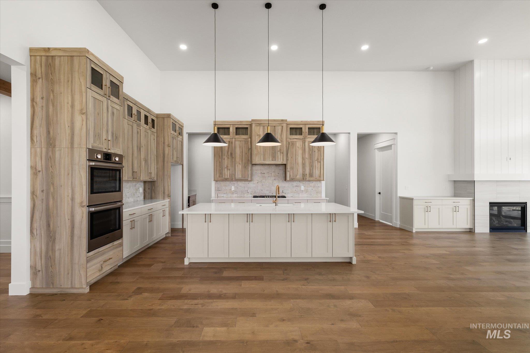 Kitchen featuring a spacious island, decorative backsplash, pendant lighting, dark wood-type flooring, and recessed lighting