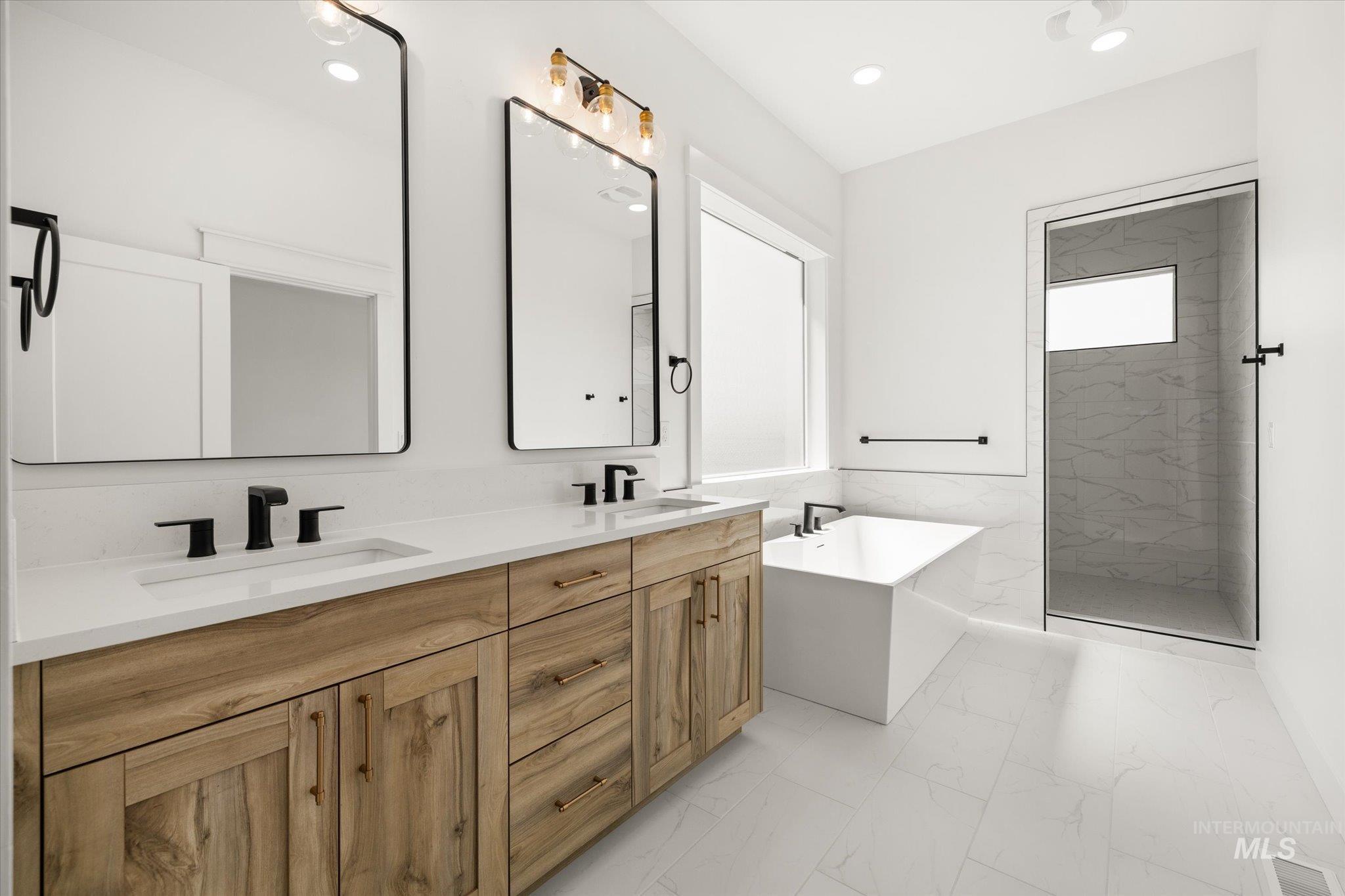 Bathroom with a soaking tub, double vanity, a marble finish shower, light marble finish flooring, and recessed lighting