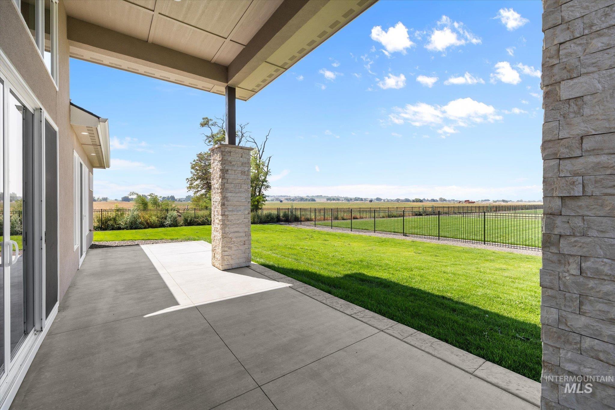 Fenced backyard with a patio area and a rural view