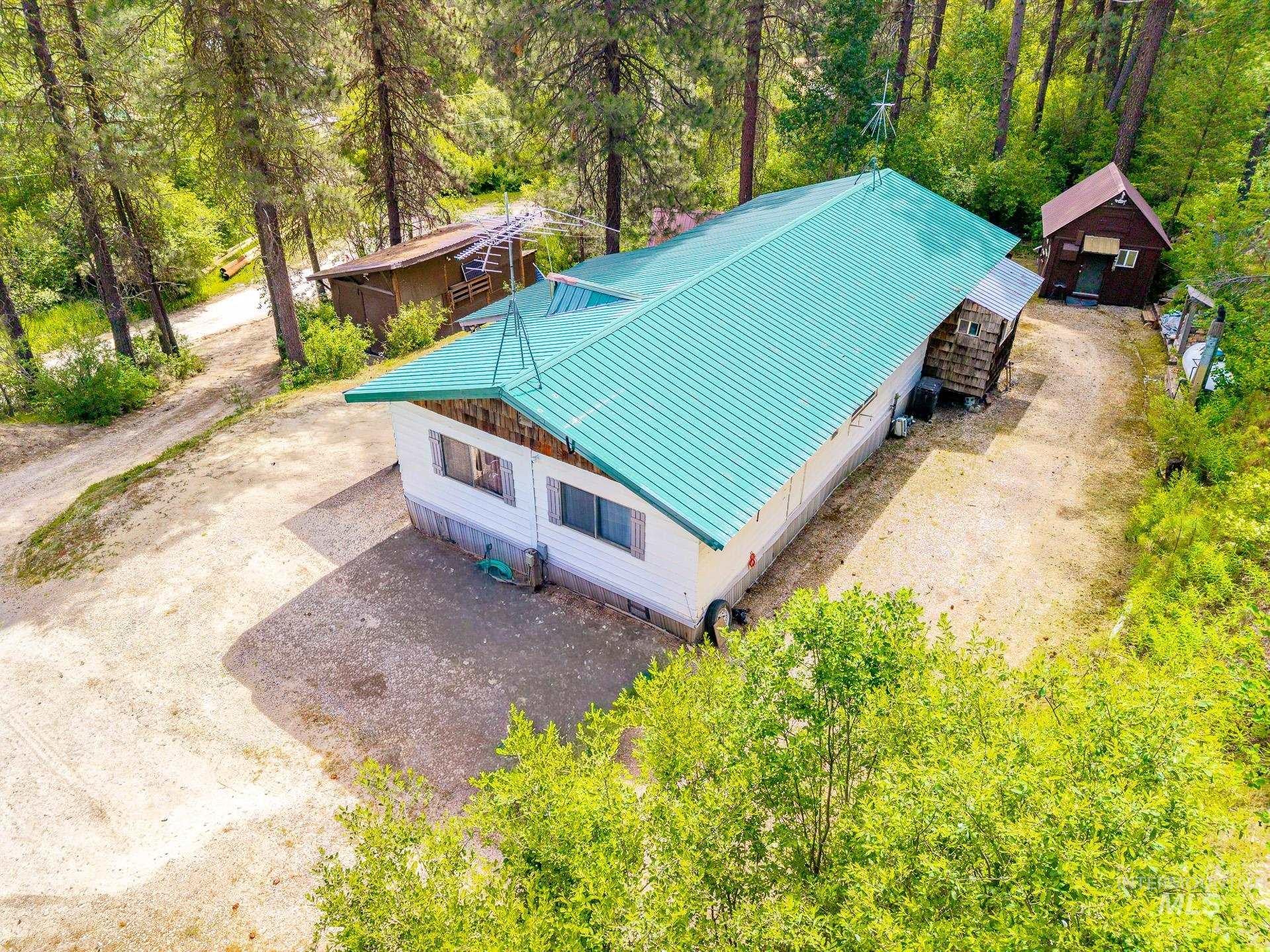 Green metal roof on a single-story dwelling surrounded by mature trees
