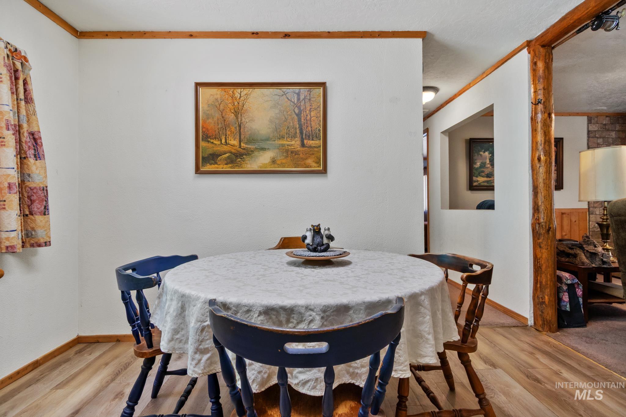 Dining area featuring wood-finish flooring, white walls, and natural wood trim accents