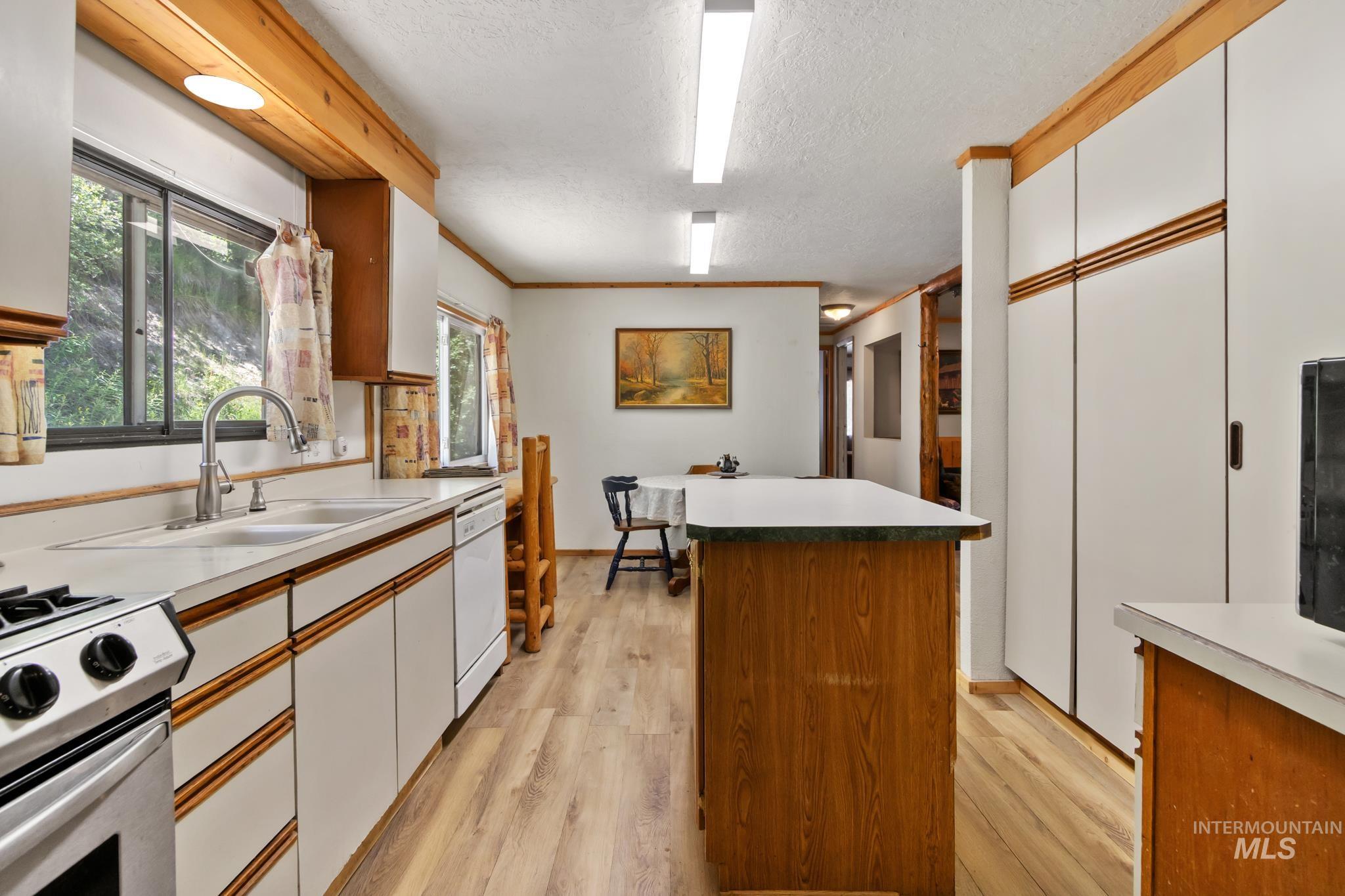 Kitchen featuring white cabinetry with wood accents, wood-finish flooring, and a stainless steel oven/range