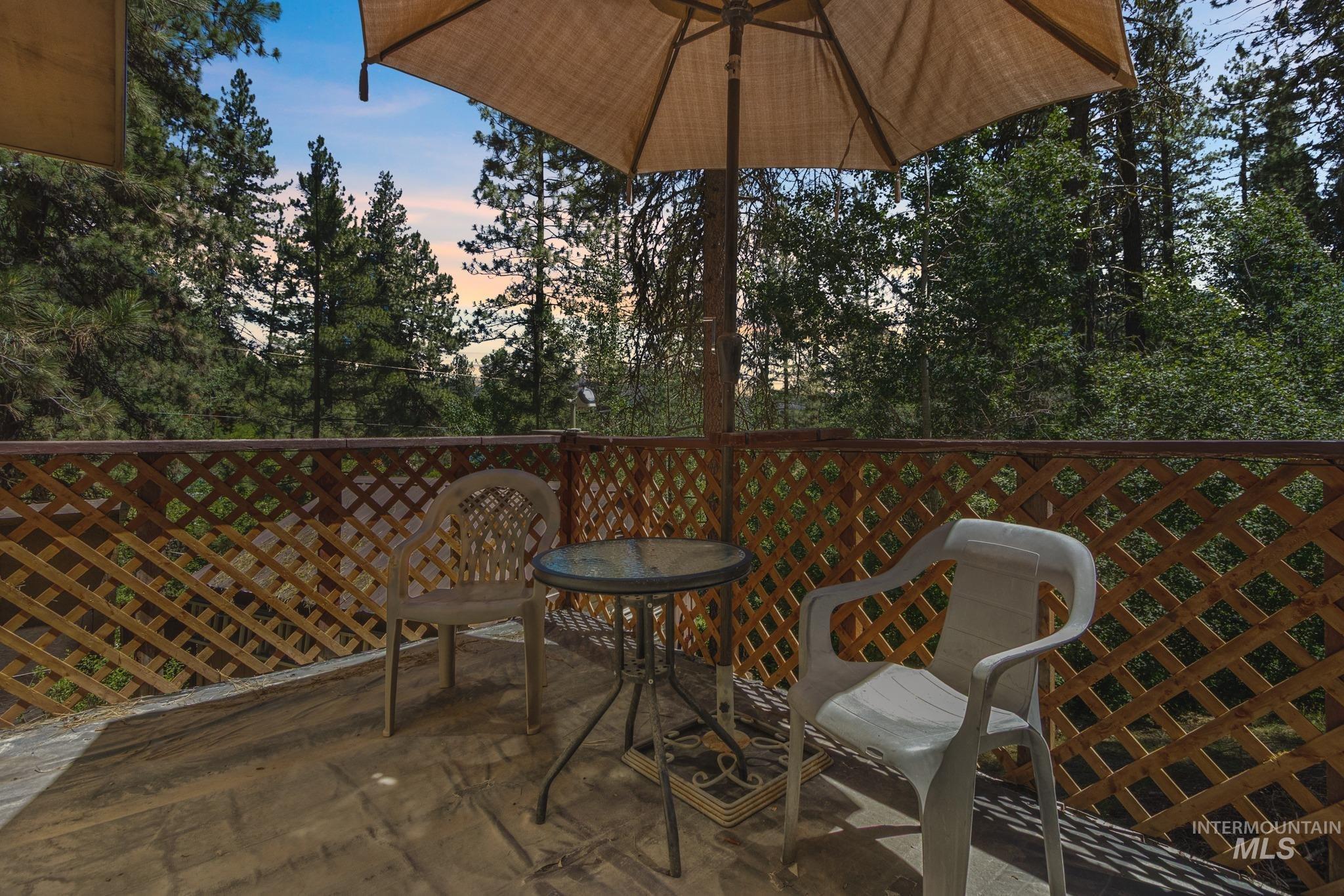 Expansive outdoor deck featuring a lattice wood railing and treed surroundings