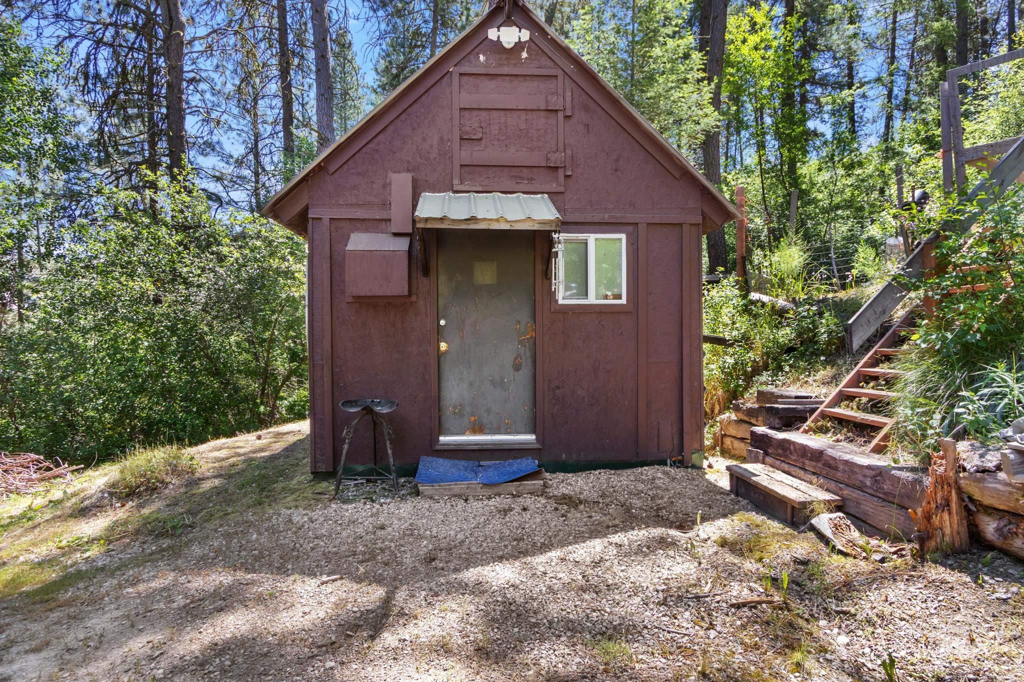Brown-sided structure featuring a gabled roof and white-framed window